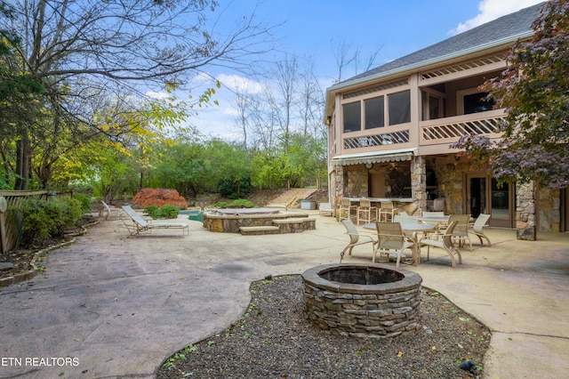 view of patio / terrace featuring exterior bar, a jacuzzi, a balcony, and an outdoor fire pit