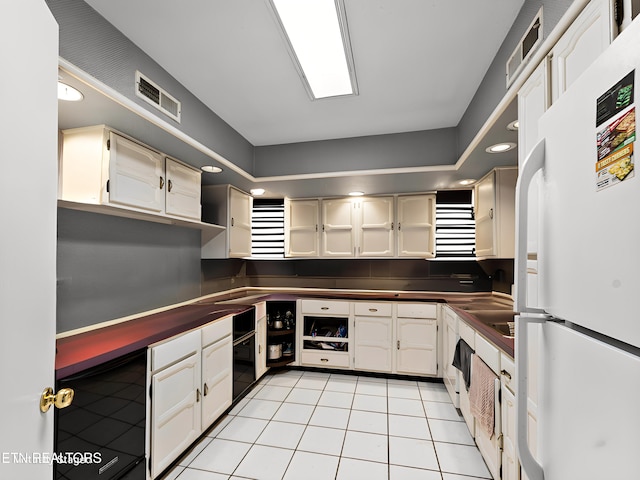 kitchen featuring white refrigerator, light tile patterned floors, and white cabinetry