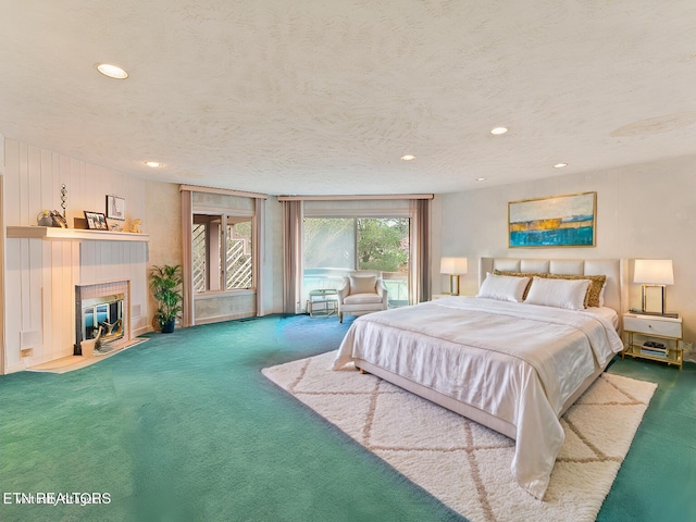 carpeted bedroom featuring a textured ceiling and a tiled fireplace