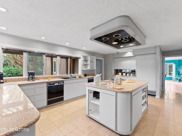 kitchen with dishwasher, a textured ceiling, white cabinetry, and a kitchen island