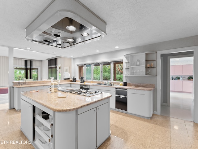 kitchen featuring a textured ceiling, a center island, white cabinetry, and plenty of natural light