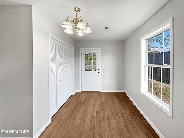 doorway to outside with a chandelier and wood-type flooring