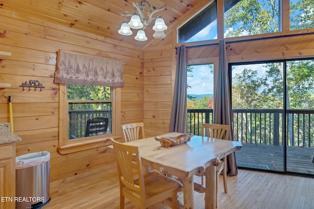 dining space with wooden walls, wooden ceiling, vaulted ceiling, and light wood-type flooring