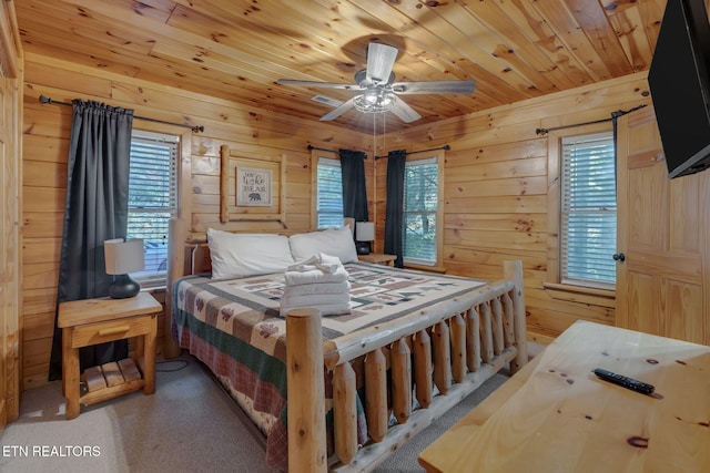 carpeted bedroom with wood walls, multiple windows, wooden ceiling, and ceiling fan