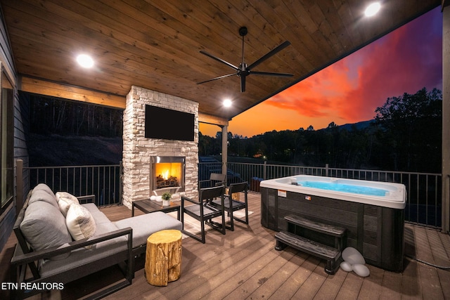 deck with ceiling fan, a hot tub, and an outdoor living space with a fireplace