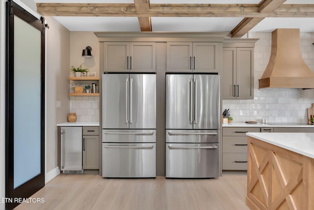 kitchen featuring backsplash, custom exhaust hood, a barn door, and stainless steel fridge