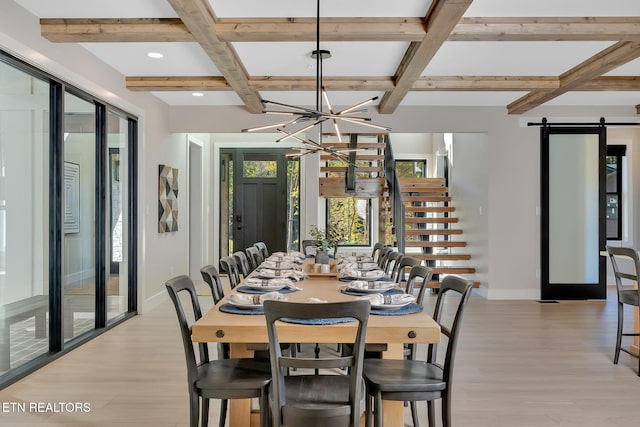 dining space featuring coffered ceiling, beamed ceiling, a barn door, an inviting chandelier, and light hardwood / wood-style floors