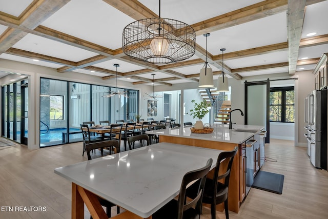 dining area with a barn door, light hardwood / wood-style floors, and plenty of natural light