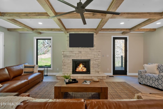 living room with light hardwood / wood-style floors, coffered ceiling, beam ceiling, and a fireplace