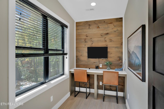 office area with built in desk, vaulted ceiling, light hardwood / wood-style flooring, and plenty of natural light