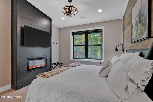 bedroom featuring a large fireplace and light wood-type flooring