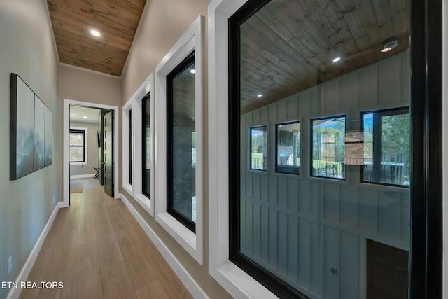 corridor with light hardwood / wood-style floors and wood ceiling