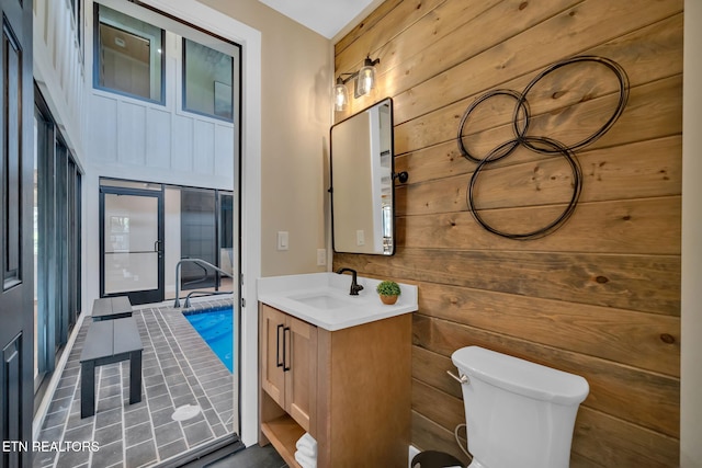 bathroom with vanity, toilet, and wood walls