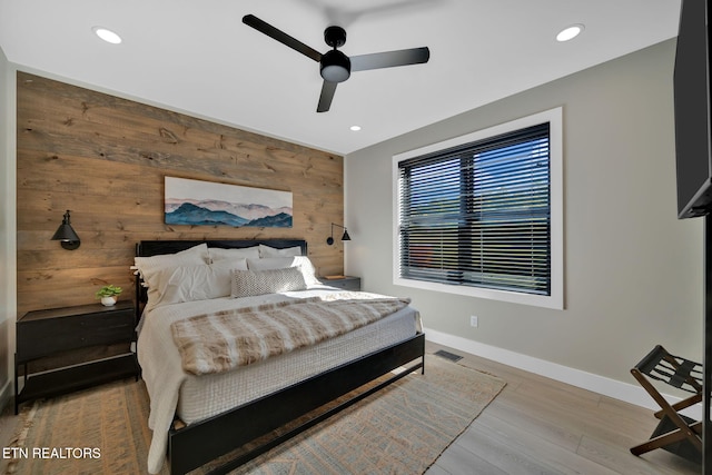 bedroom with wood walls, wood-type flooring, and ceiling fan