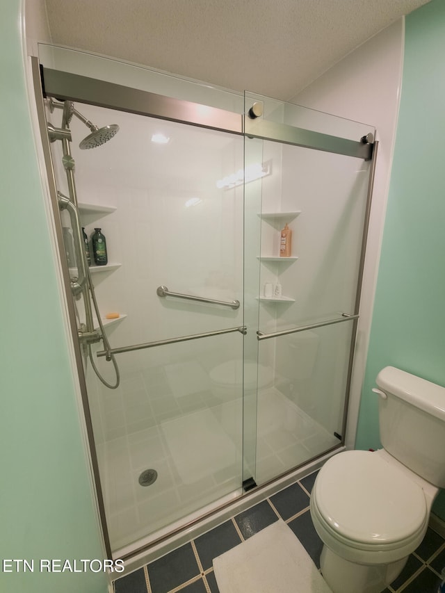 bathroom featuring toilet, a textured ceiling, and a shower with shower door