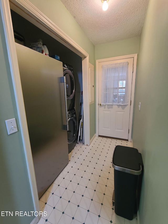 doorway to outside with stacked washer and dryer and a textured ceiling