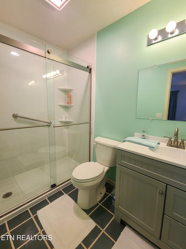 bathroom with vanity, toilet, a textured ceiling, and a shower with shower door