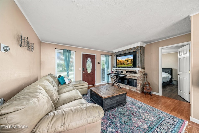 living room featuring crown molding, a textured ceiling, wood-type flooring, and a brick fireplace