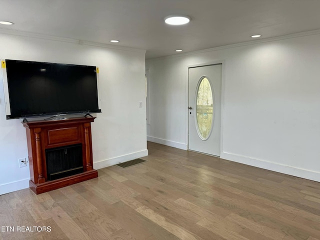 unfurnished living room featuring light hardwood / wood-style flooring and ornamental molding