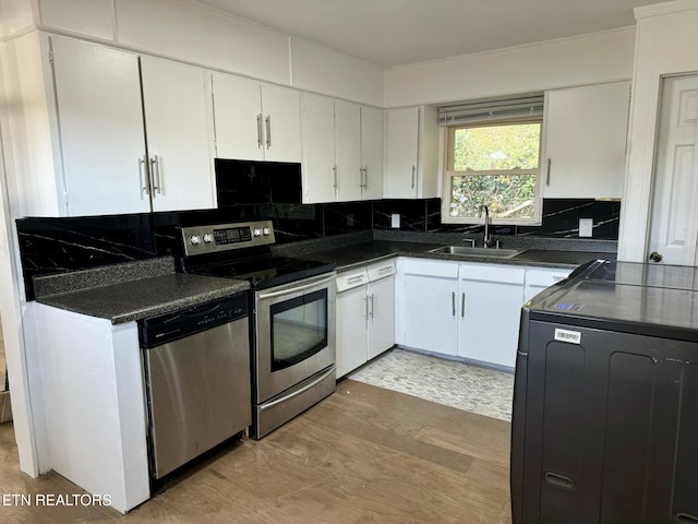 kitchen featuring appliances with stainless steel finishes, washer / clothes dryer, white cabinetry, and light hardwood / wood-style flooring