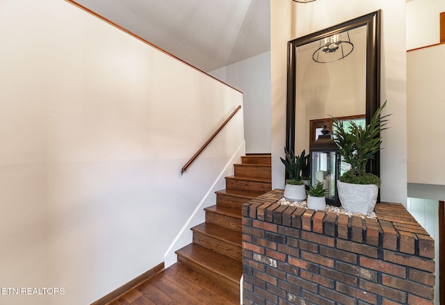 stairs featuring wood-type flooring and vaulted ceiling