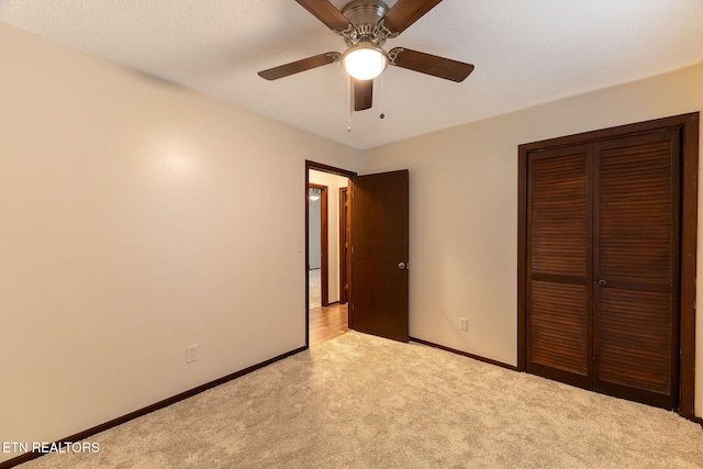 unfurnished bedroom with a textured ceiling, light colored carpet, ceiling fan, and a closet