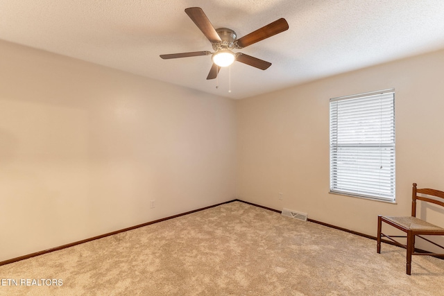 empty room with a textured ceiling, light carpet, and ceiling fan