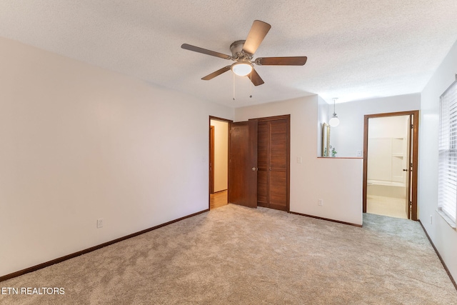 unfurnished bedroom with a closet, connected bathroom, a textured ceiling, light carpet, and ceiling fan