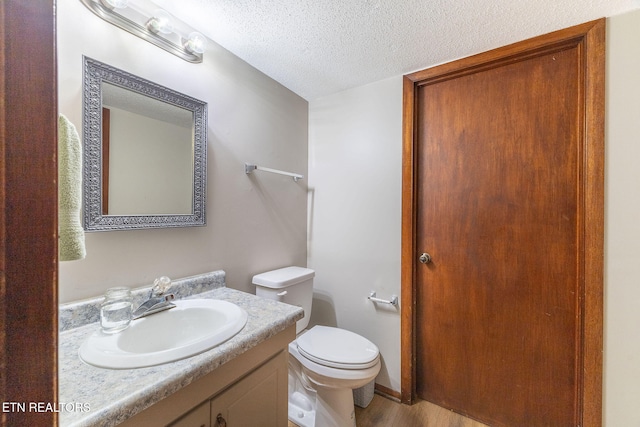 bathroom featuring wood-type flooring, a textured ceiling, toilet, and vanity