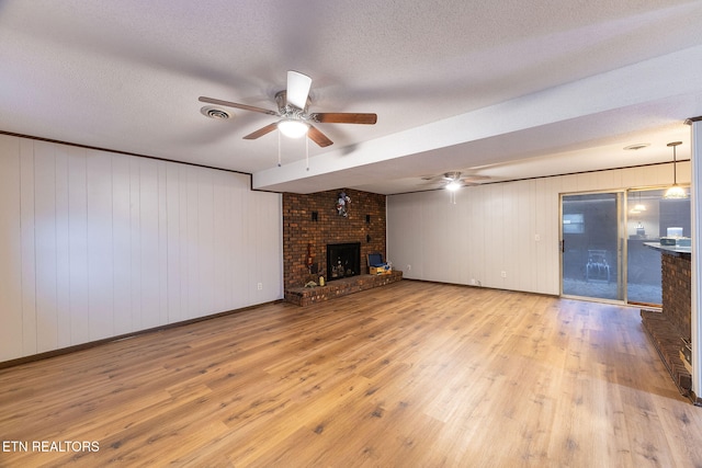 unfurnished living room featuring a fireplace, ceiling fan, a textured ceiling, and light wood-type flooring