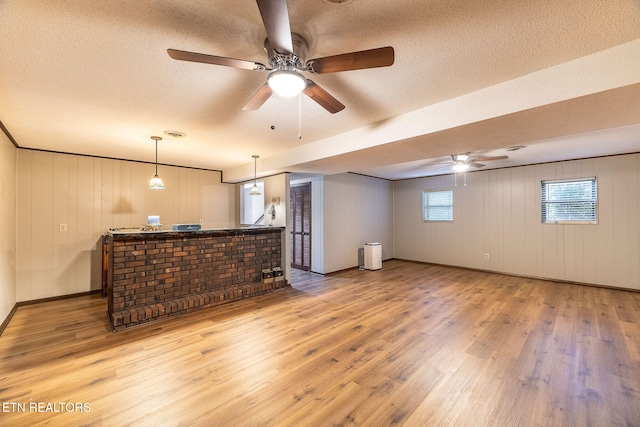 interior space featuring bar area, a textured ceiling, wood walls, hardwood / wood-style flooring, and ceiling fan