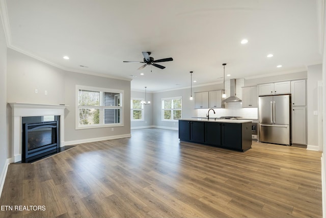 kitchen featuring a center island with sink, light hardwood / wood-style flooring, wall chimney exhaust hood, white cabinetry, and stainless steel refrigerator