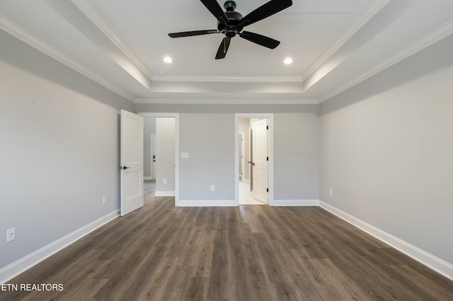 unfurnished bedroom with a raised ceiling, ceiling fan, dark wood-type flooring, and ornamental molding