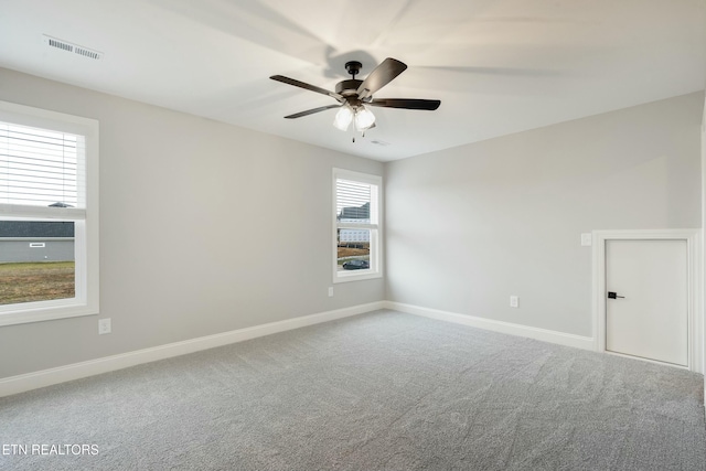 carpeted empty room featuring ceiling fan and a wealth of natural light