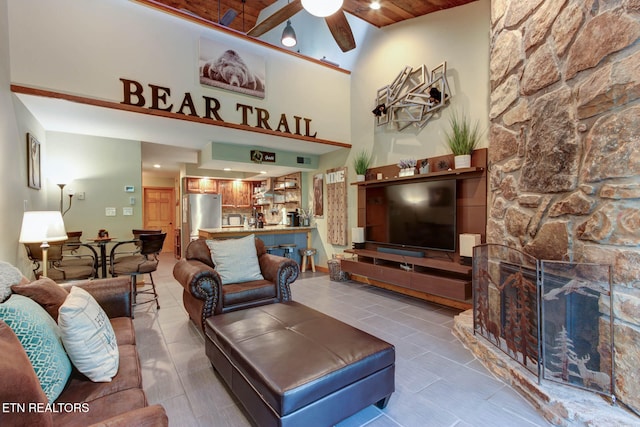 tiled living room with ceiling fan and high vaulted ceiling