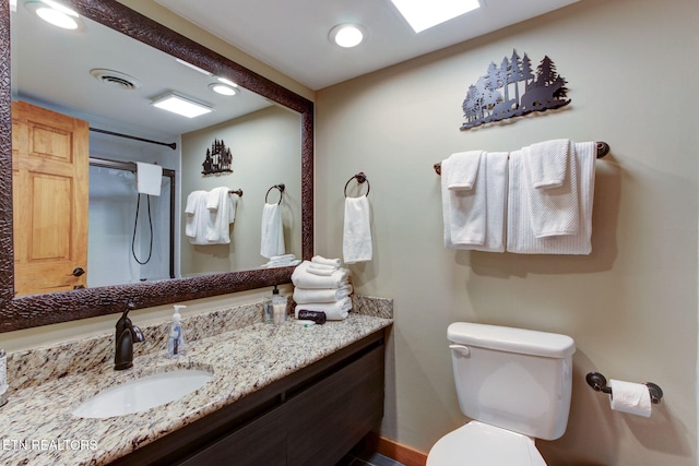 bathroom featuring toilet, walk in shower, and vanity