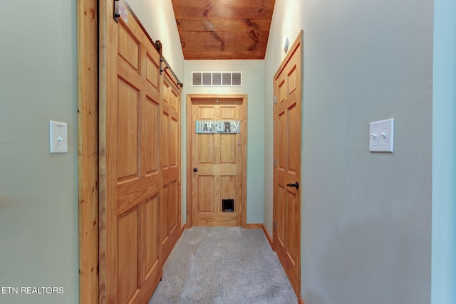 doorway featuring light carpet, wooden ceiling, and a barn door