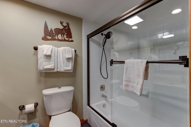 bathroom featuring combined bath / shower with glass door and toilet