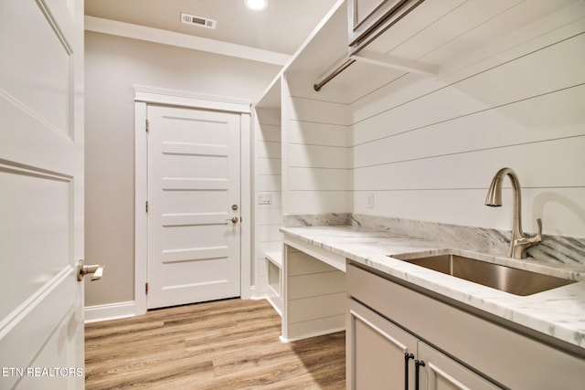 clothes washing area featuring visible vents, light wood-type flooring, baseboards, and a sink