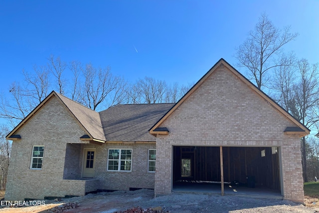 exterior space with brick siding, an attached garage, and a shingled roof