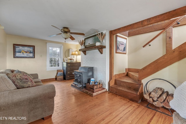 living room with light hardwood / wood-style flooring, a wood stove, and ceiling fan