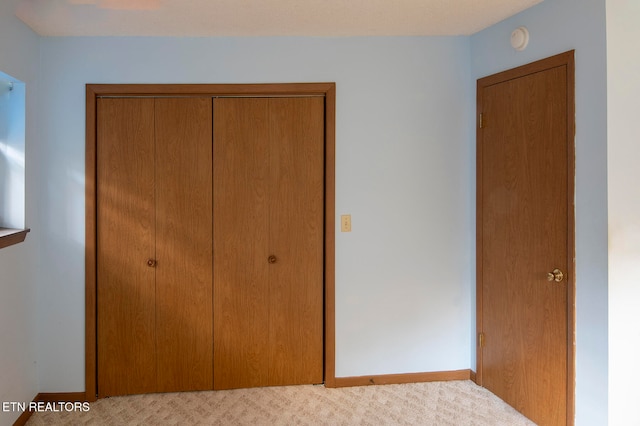 unfurnished bedroom featuring light colored carpet and a closet