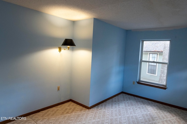 spare room featuring a textured ceiling and light colored carpet