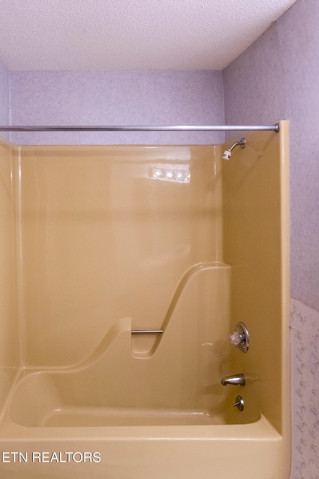 bathroom featuring a textured ceiling and tub / shower combination