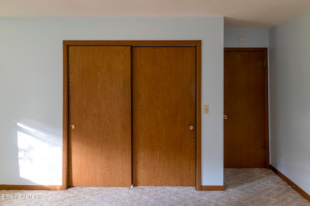 unfurnished bedroom featuring light colored carpet and a closet