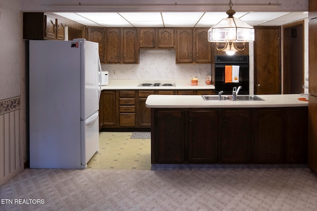 kitchen featuring white appliances, an inviting chandelier, sink, decorative light fixtures, and kitchen peninsula