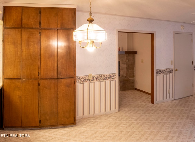 unfurnished dining area with light colored carpet and a notable chandelier