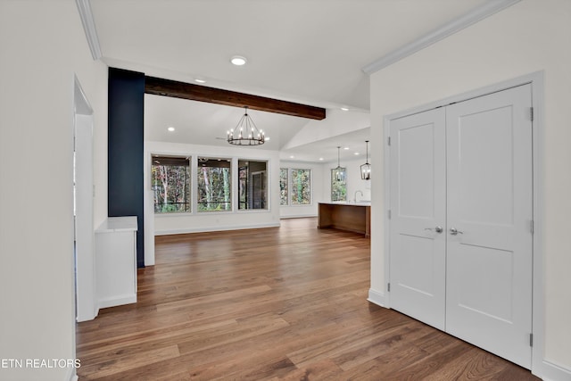 interior space featuring crown molding, hardwood / wood-style flooring, lofted ceiling with beams, and a chandelier