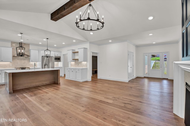 kitchen featuring lofted ceiling with beams, hanging light fixtures, stainless steel appliances, and light hardwood / wood-style floors