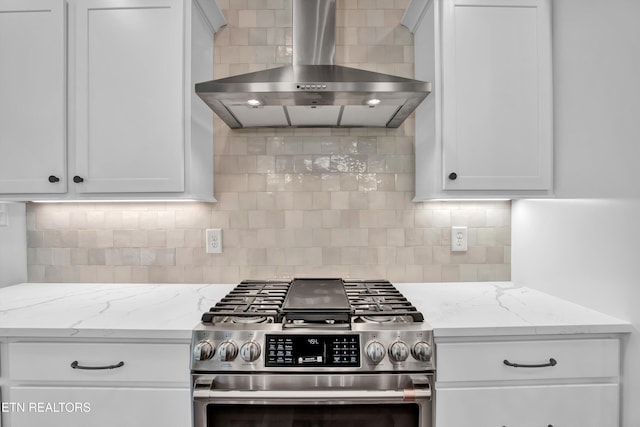 kitchen featuring wall chimney range hood, white cabinetry, and high end stove